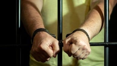 Arrestan a tres infractores 1 man handcuffs cell behind bars 260nw 2158053719 2